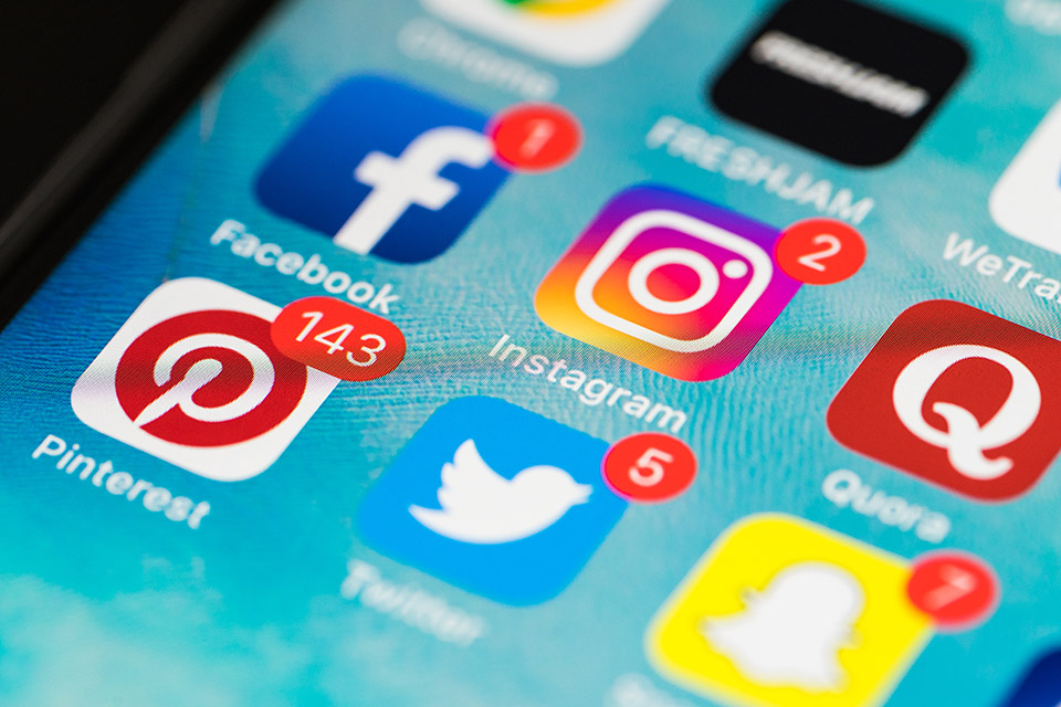 Nahaufnahme von einem Smartphone-Screen auf dem verschiedene Social-Media-App-Icons zu sehen sind.